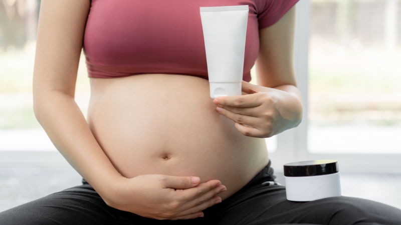 Trudnica drži gel za hemoroide i pridržava stomak dok sedi